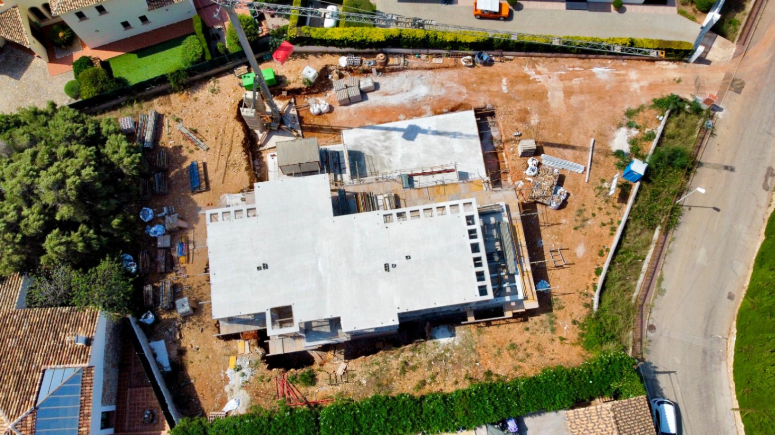 Vue aérienne de l'état d'avancement des travaux sur le terrain plat, illustrant la structure en béton et la grue de chantier à Jávea.
