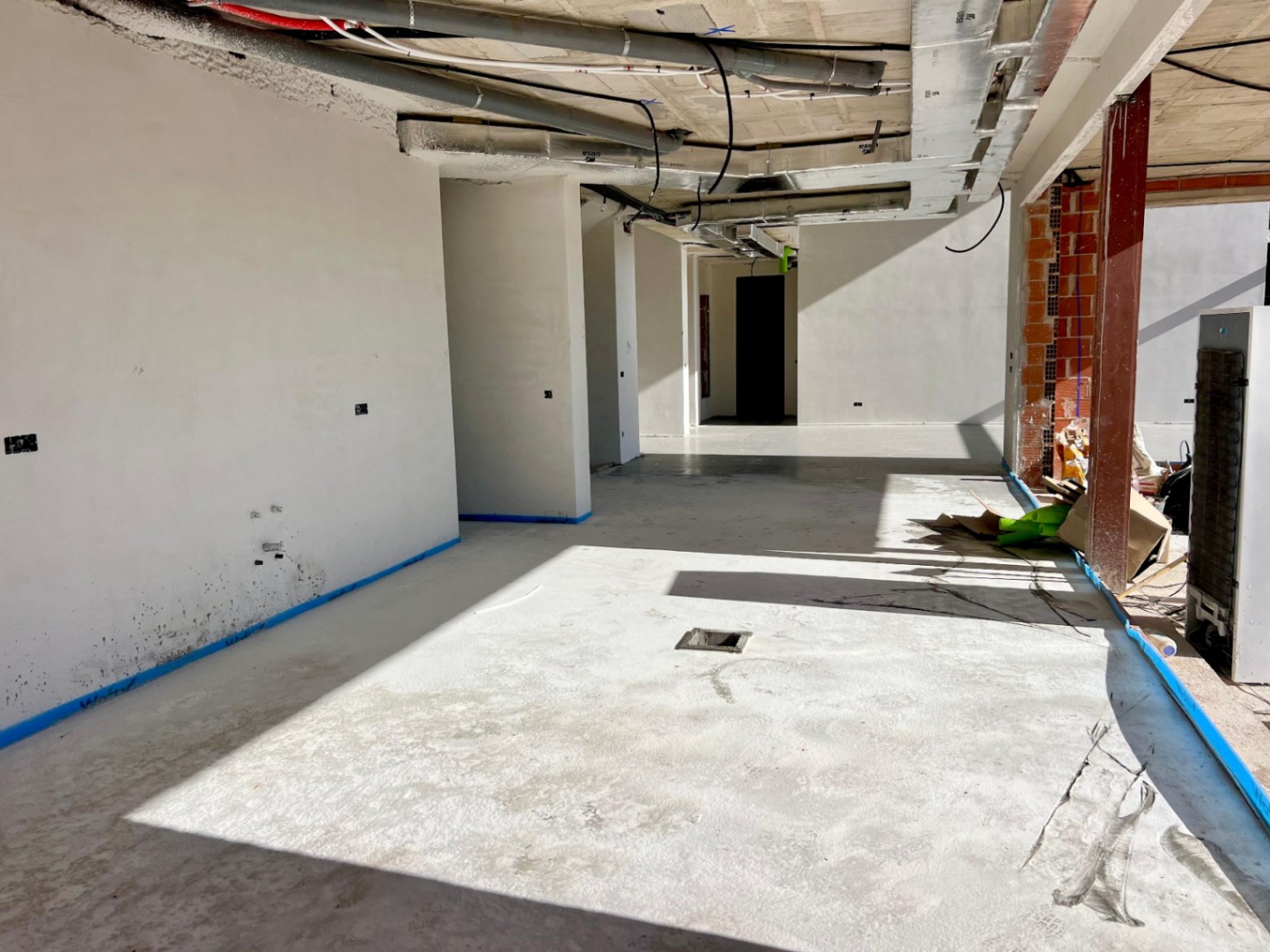 Vue intérieure en phase de construction avec murs plâtrés, gaines techniques apparentes et un agencement ouvert optimisant la lumière naturelle.