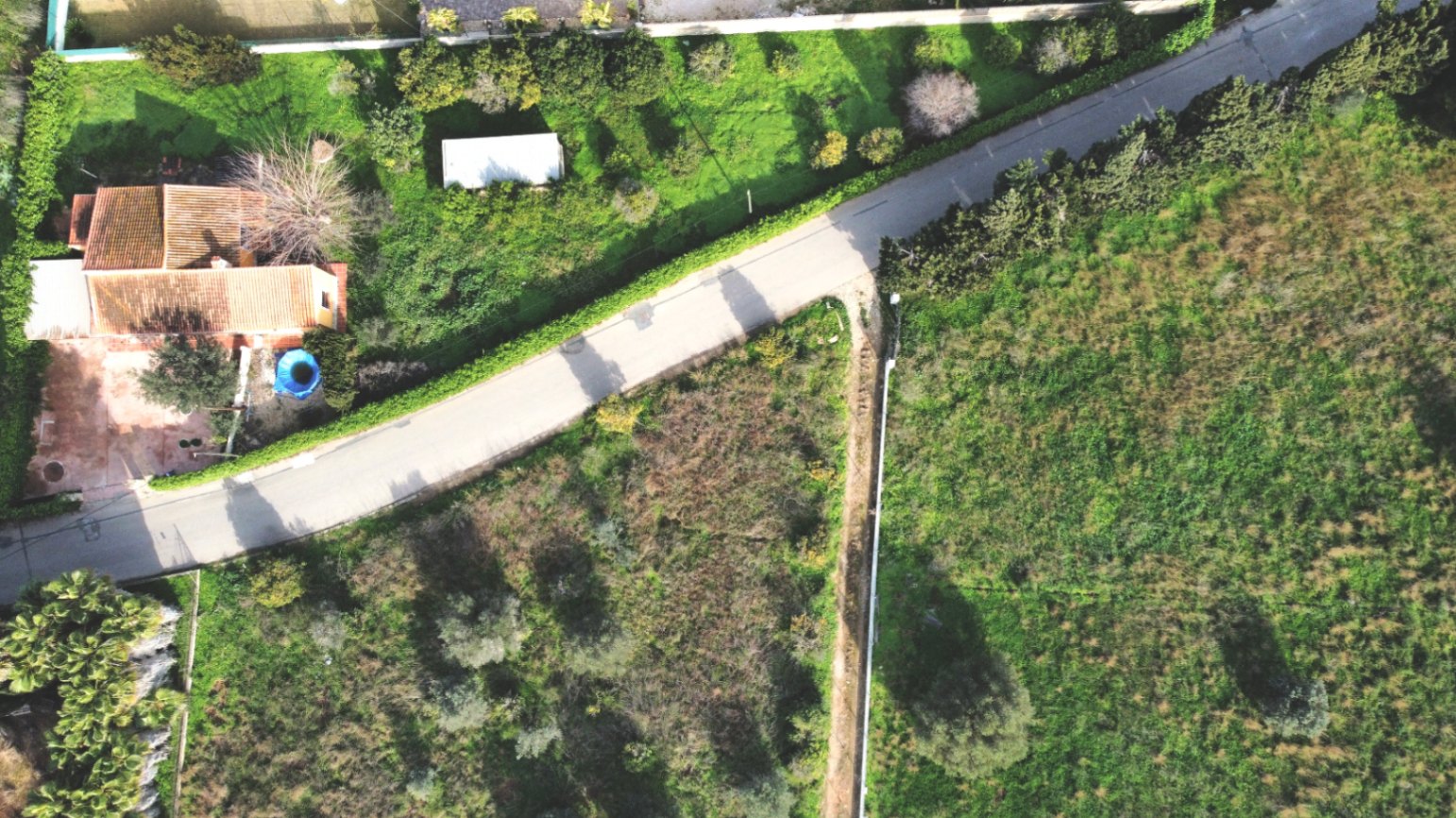 Vue aérienne montrant la maison individuelle, son grand terrain de 1 414 m² avec arbres fruitiers et le paysage rural environnant.