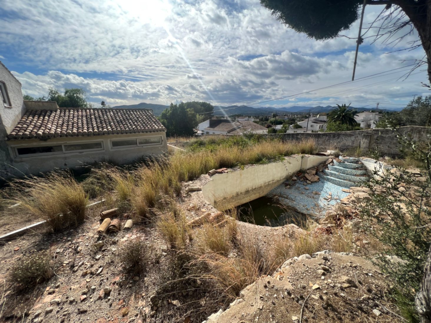 Piscine à rénover avec escaliers romains, offrant une vue dégagée sur les montagnes environnantes et le paysage naturel de Jávea.