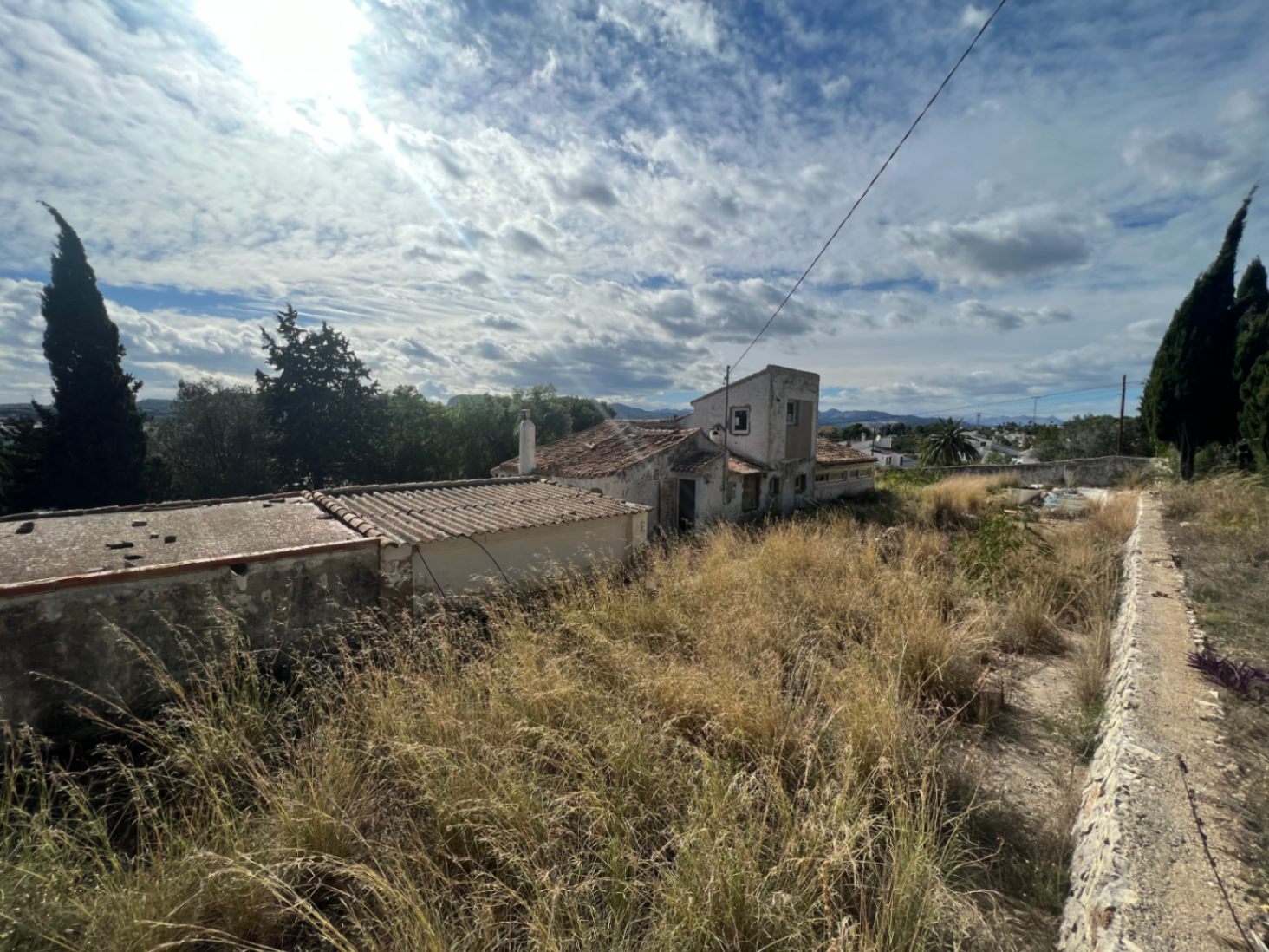 Vue extérieure de la bâtisse originale et de ses annexes sur un grand terrain arboré, soulignant le fort potentiel de rénovation et l'architecture traditionnelle locale.
