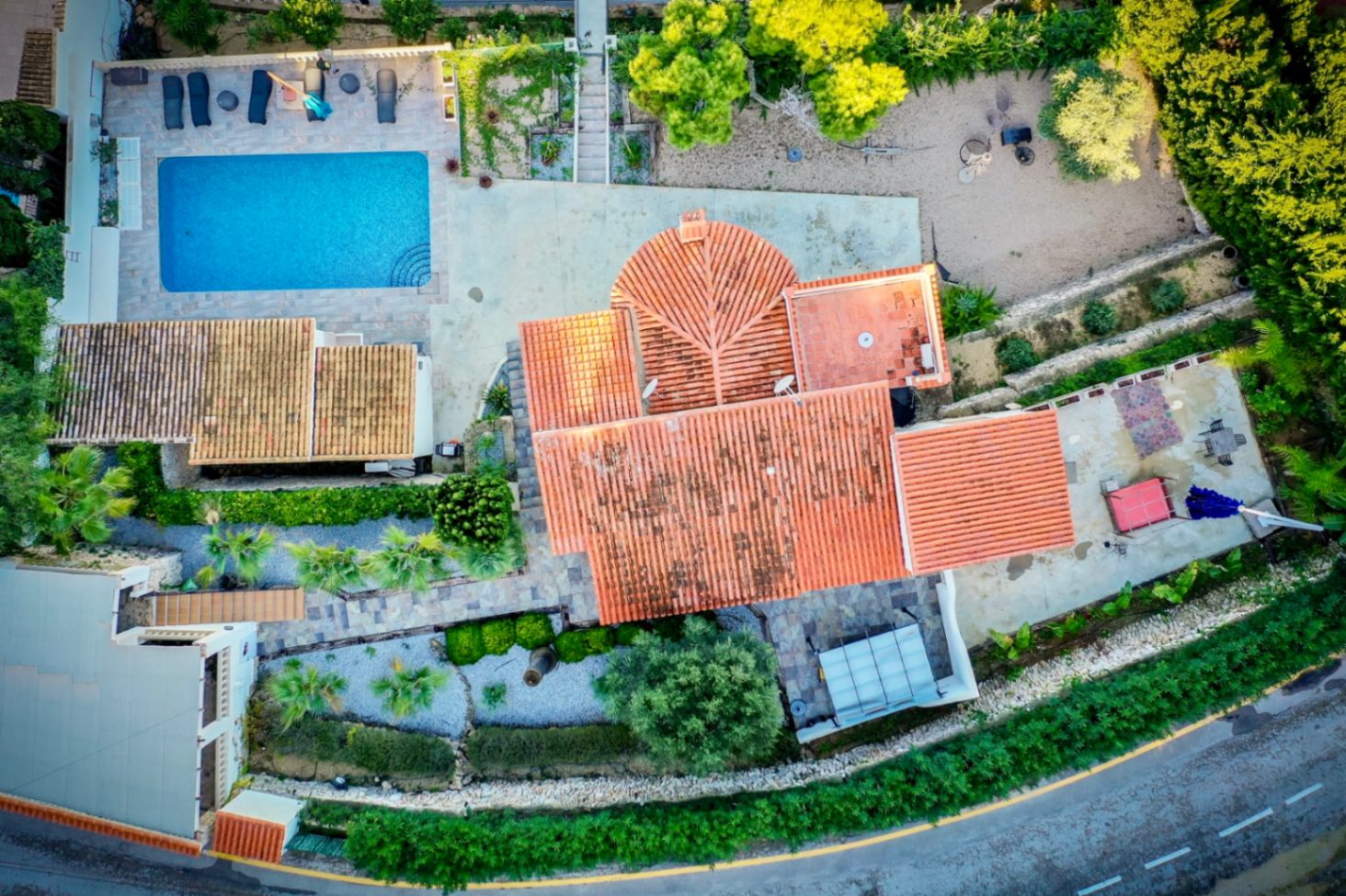 Vue aérienne de la propriété révélant la piscine rectangulaire, les terrasses en pierre et la toiture en tuiles traditionnelles au cœur d'un jardin méditerranéen aménagé.