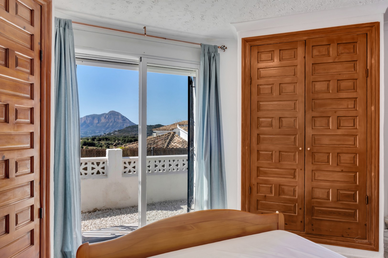 Chambre avec placard intégré en bois et accès direct à une terrasse offrant une vue panoramique sur le Montgó et les environs.