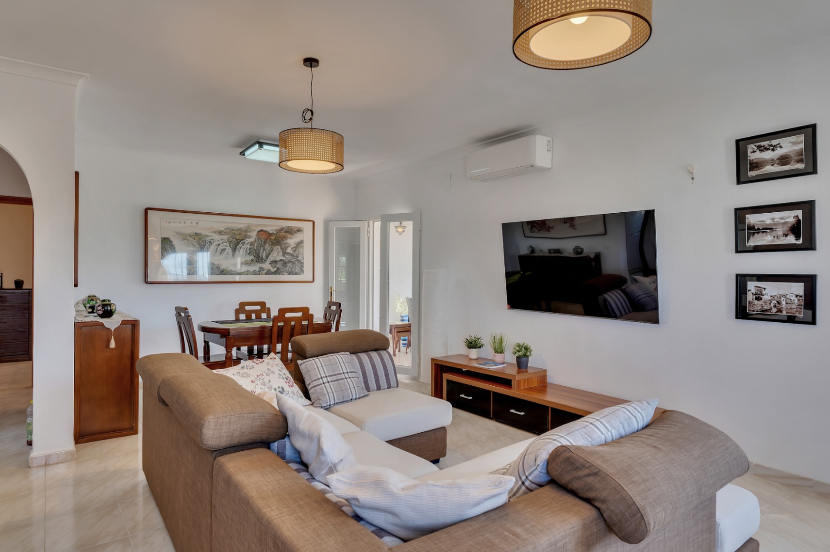 Salon et salle à manger à aire ouverte avec canapé d'angle, mobilier en bois et suspensions en fibres naturelles. Équipé de la climatisation et de sols en grès cérame.