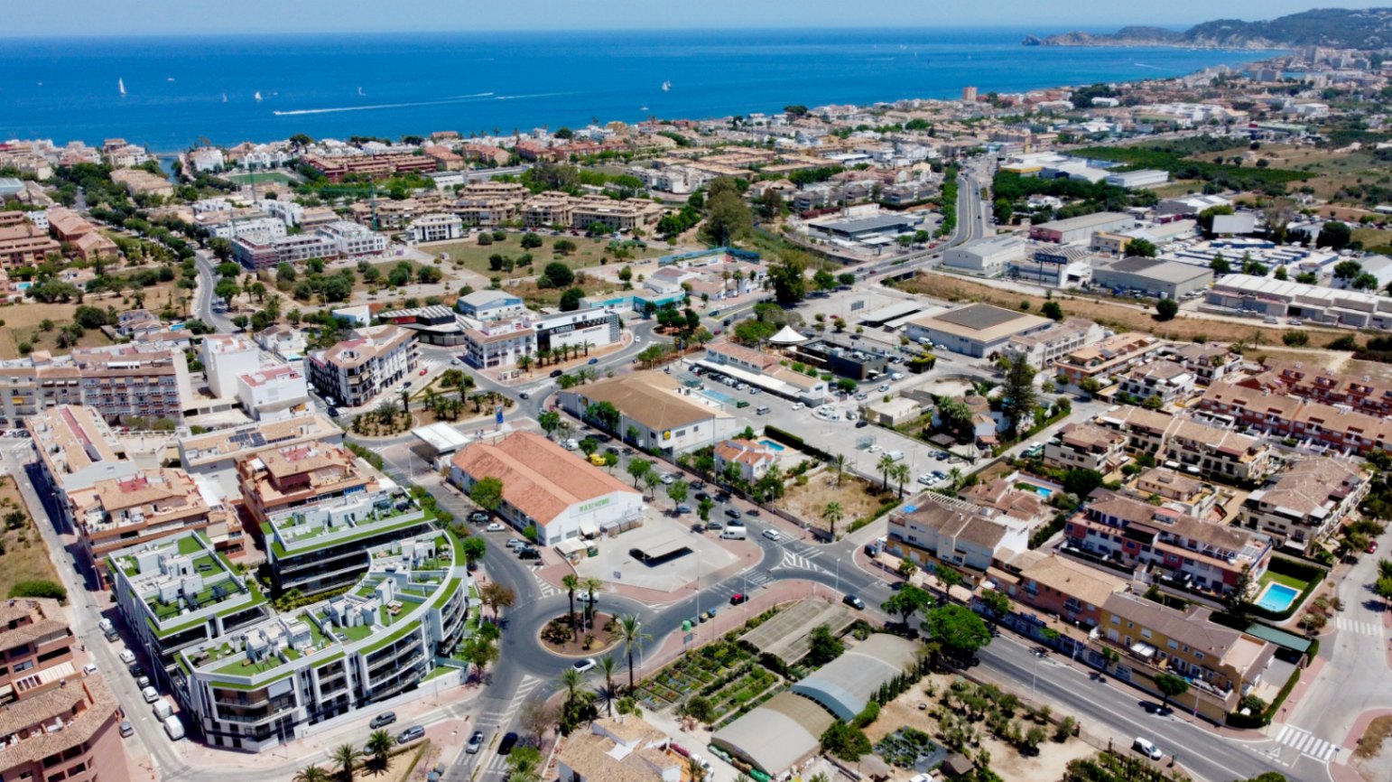 Vue aérienne du bâtiment moderne aux toits-terrasses végétalisés, situé dans un quartier central entre la vieille ville et le port de Jávea, à proximité du littoral.