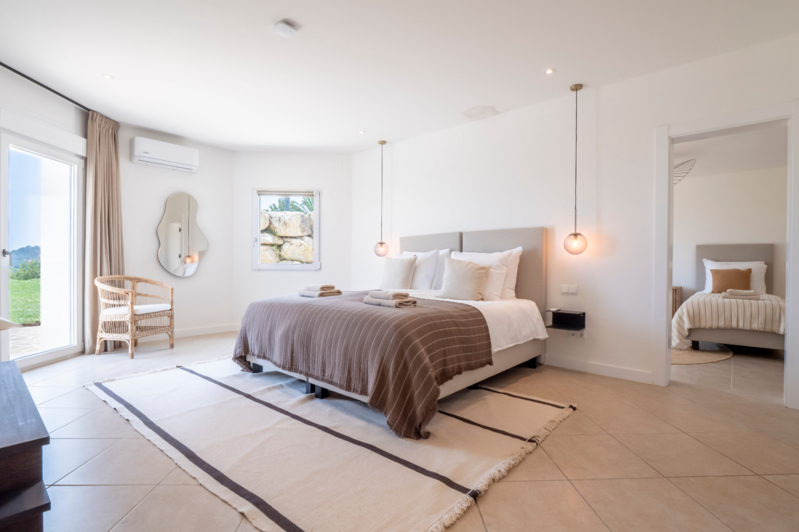 Chambre lumineuse avec lit double, tapis rayé et vue sur le jardin.