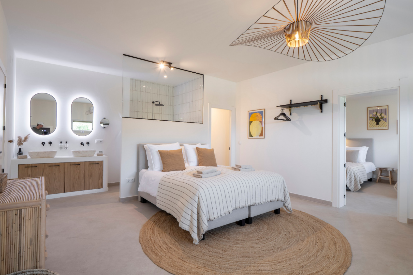 Chambre lumineuse avec salle de bain intégrée et double vasque avec miroirs rétroéclairés.