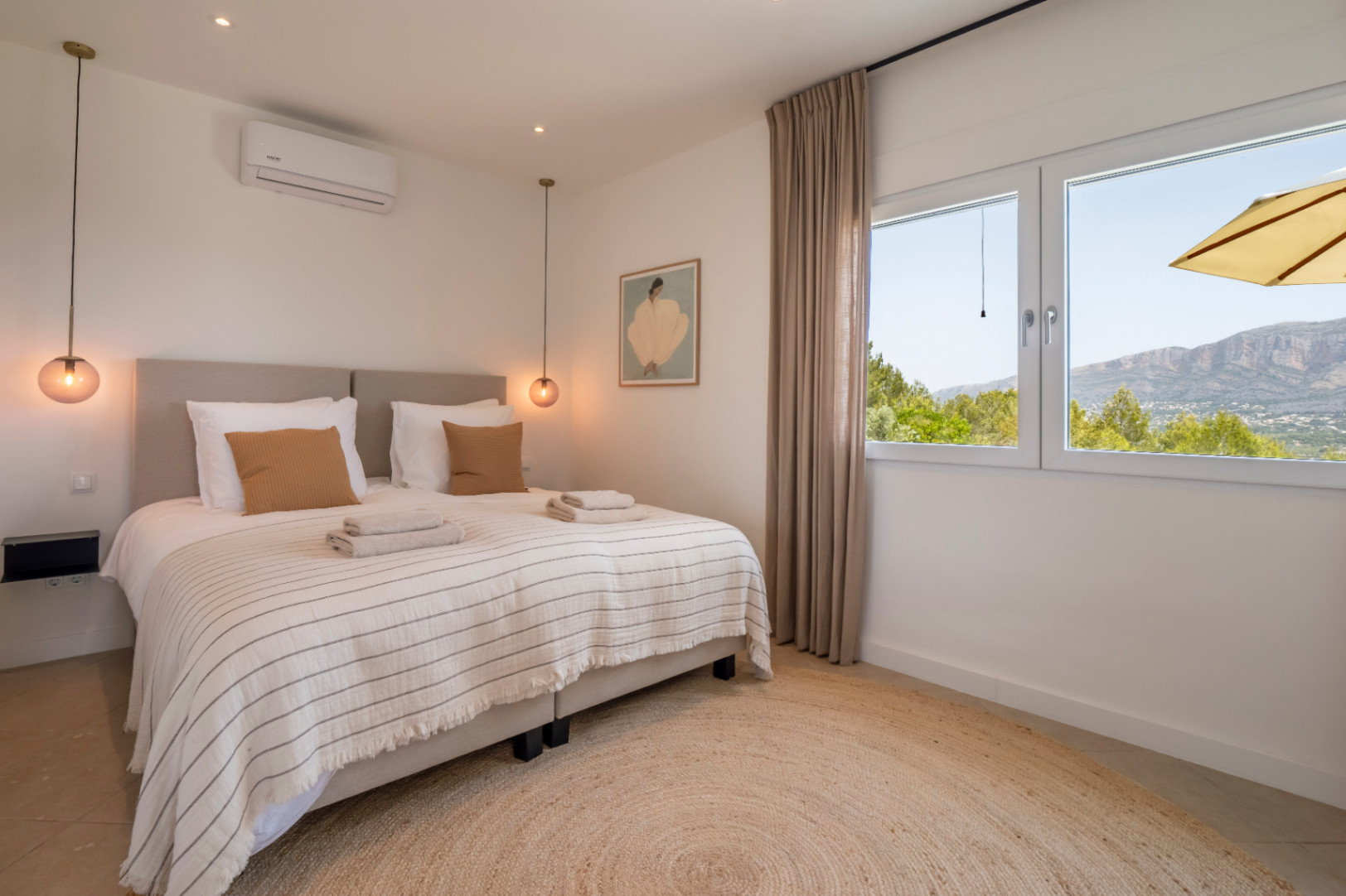 Chambre lumineuse avec tapis rond en jute et vue sur la montagne.