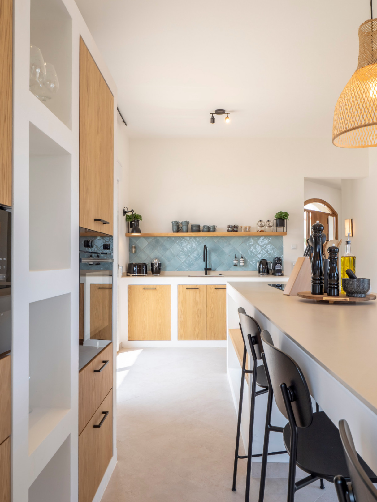 Cuisine lumineuse avec îlot central, armoires en bois clair et crédence en carreaux turquoise. Design moderne et fonctionnel.