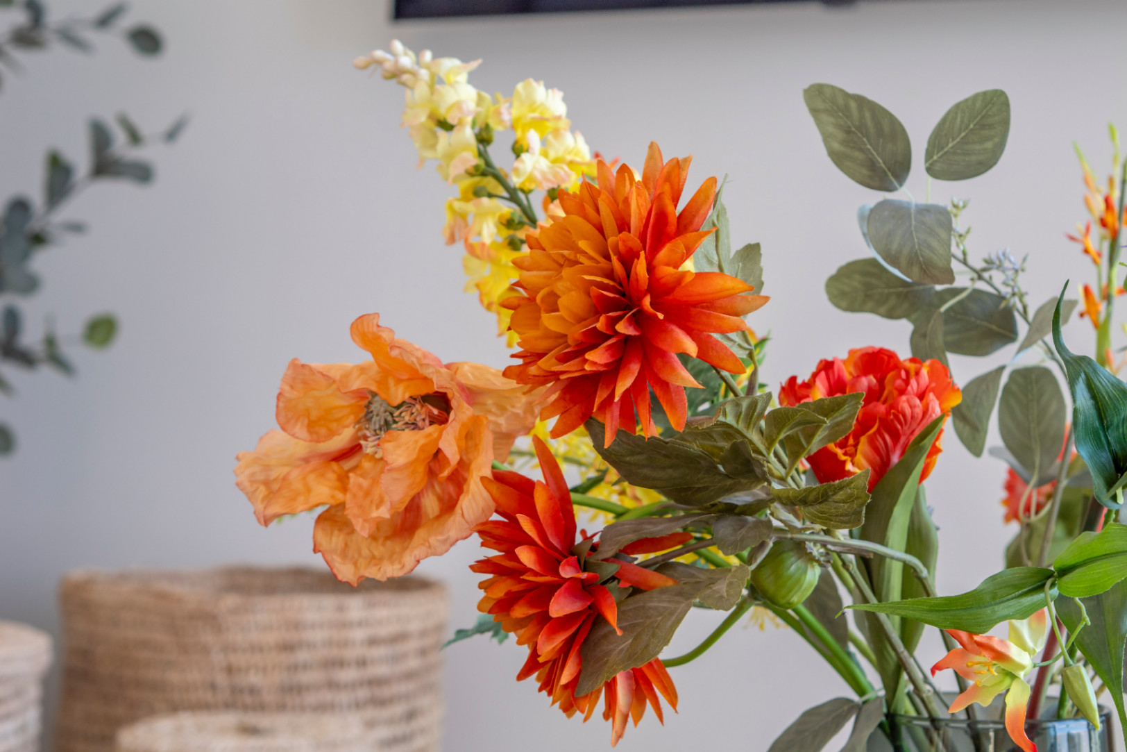 Détail floral avec dahlia orange et coquelicot dans un vase, ajoutant une touche de couleur à l'intérieur.