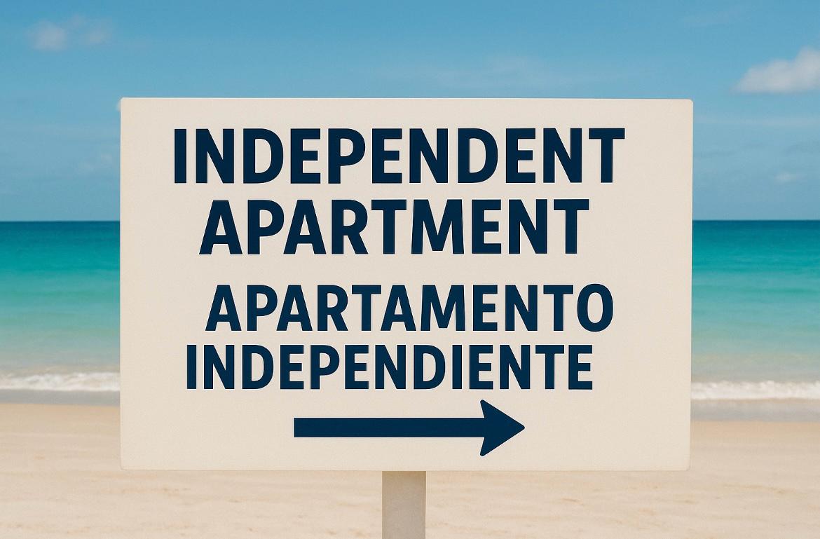 Panneau bilingue sur la plage indiquant la direction des appartements indépendants.