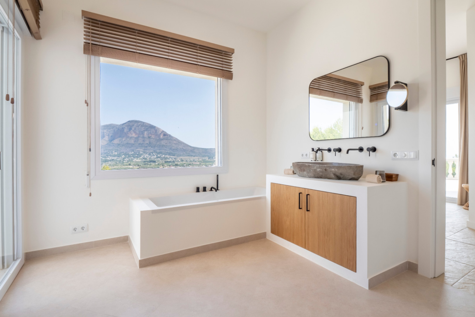 Salle de bain lumineuse avec vasque en pierre et vue sur la montagne. Design moderne et minimaliste.