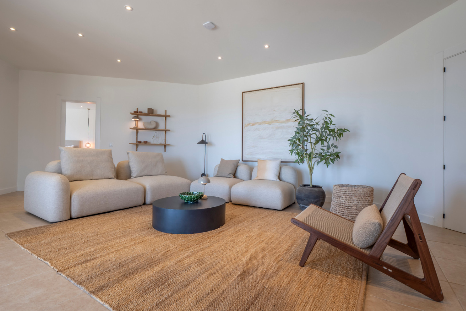 Salon lumineux avec canapés modulables beiges, tapis en jute et détails décoratifs minimalistes.