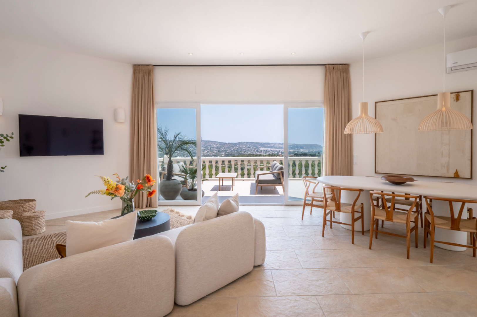 Salon-salle à manger lumineux avec accès à la terrasse et vue panoramique. Design moderne avec mobilier clair et touches naturelles.