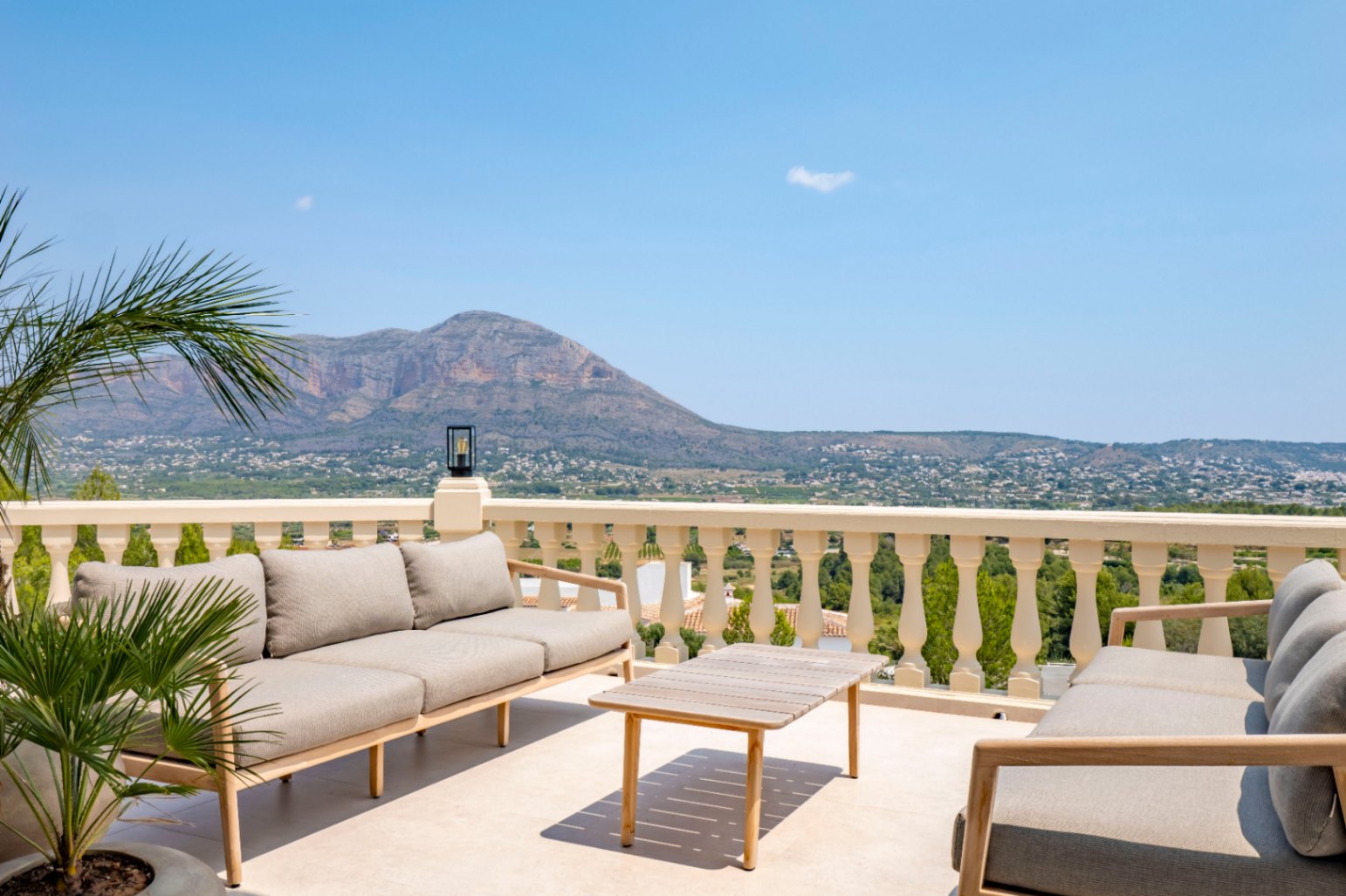 Terrasse avec balustrade classique, mobilier d'extérieur en bois et vue panoramique sur la montagne.