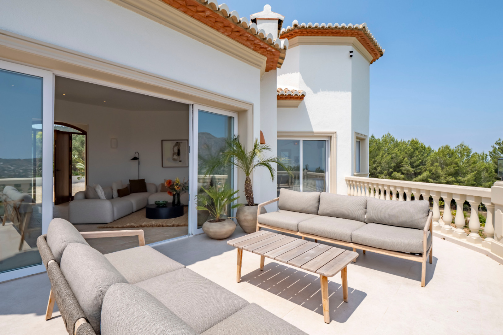 Terrasse avec vue à Jávea. Mobilier d'extérieur aux tons neutres et accès au salon.