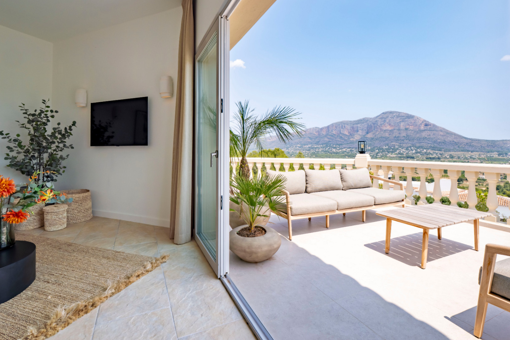 Terrasse avec vue sur la montagne, meublée d'un canapé et d'une table basse en bois clair.