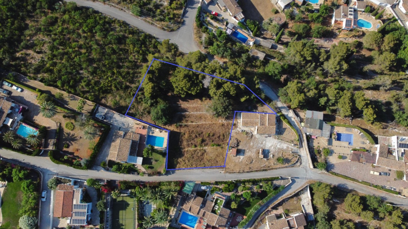 Vue aérienne délimitant le terrain de 1 908 m² à Jávea, illustrant ses restanques traditionnelles, sa zone boisée de pins et sa proximité avec les villas environnantes.