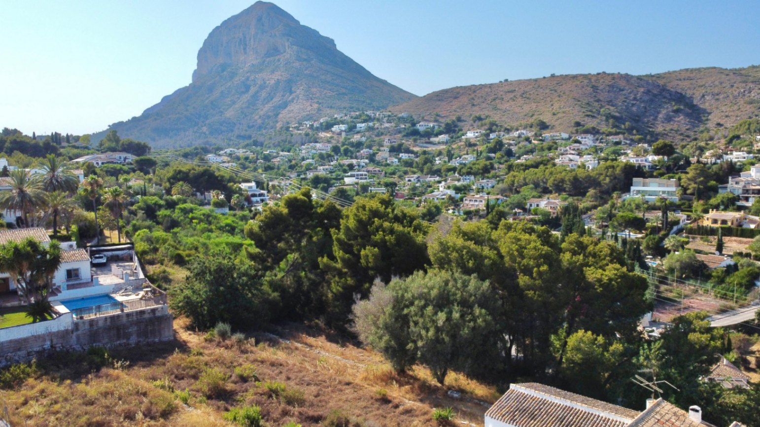 Vue panoramique sur le massif du Montgó depuis le terrain, entouré de végétation méditerranéenne et de quartiers résidentiels de Jávea.