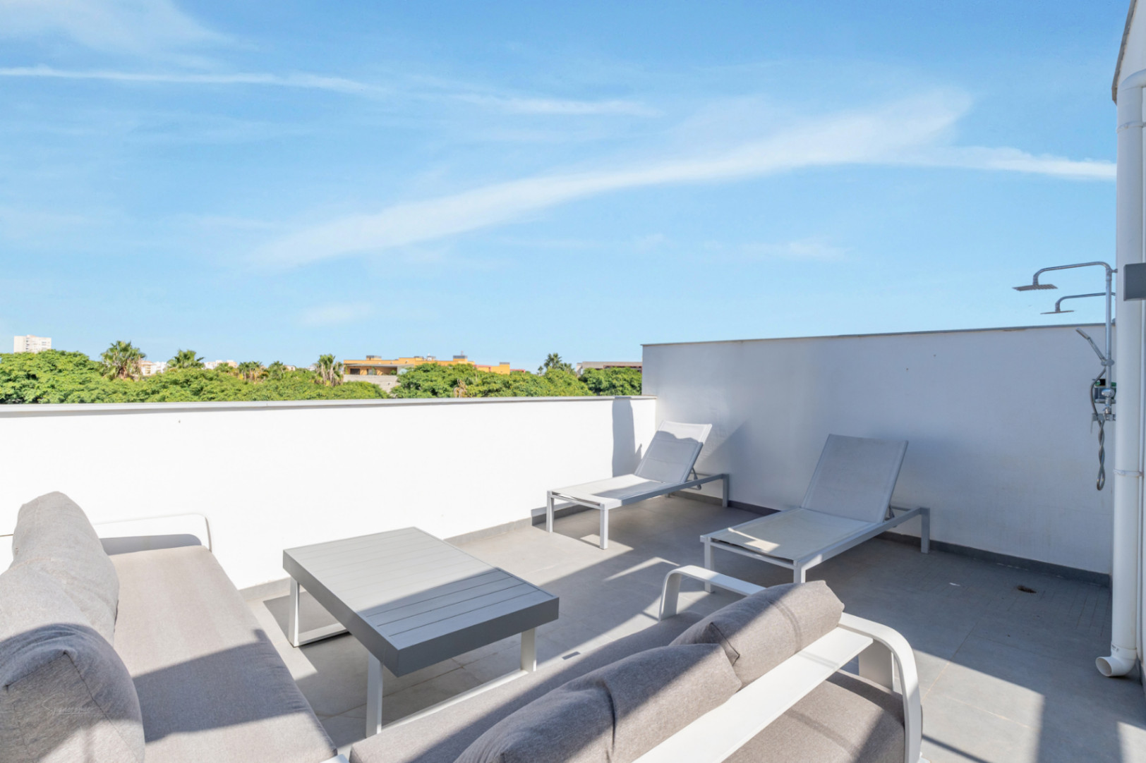 Terrasse privée sur le toit avec salon de jardin, bains de soleil et douche extérieure. L'espace offre une vue dégagée sur les zones vertes environnantes.