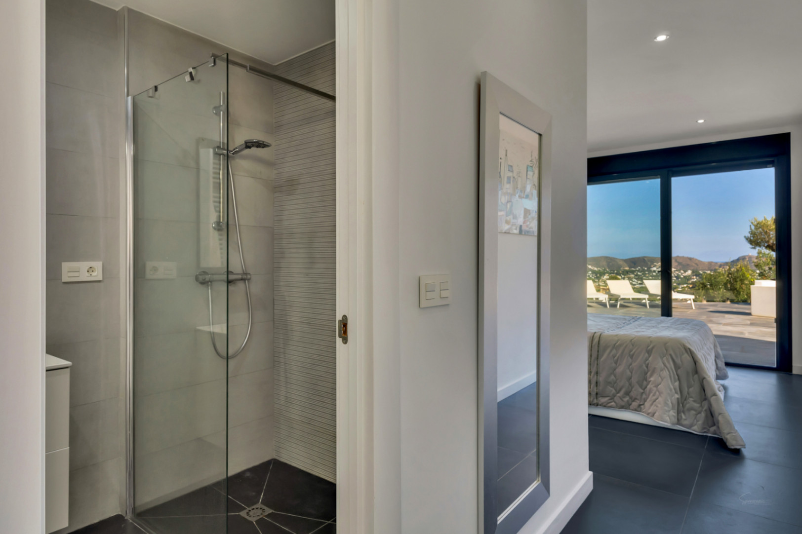 Chambre en suite avec salle de douche à l'italienne vitrée. Les grandes baies vitrées s'ouvrent sur une terrasse privée avec vue sur les montagnes.