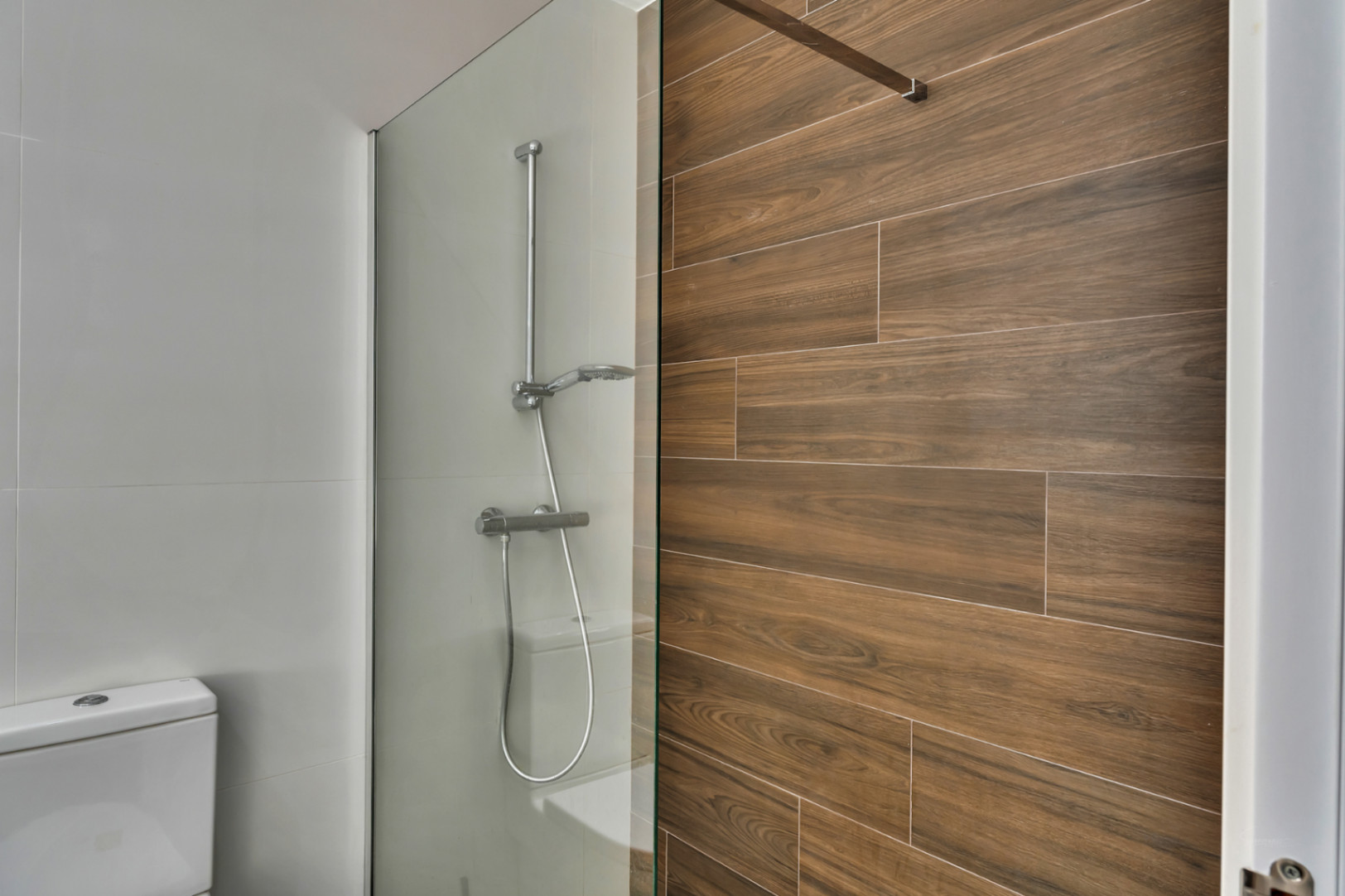 Salle de bain moderne avec douche à l'italienne, paroi en verre et mur d'accent en grès cérame effet bois.
