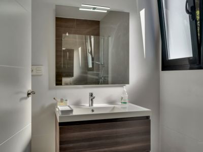 Détail de la salle de bain avec lavabo moderne et miroir éclairé.