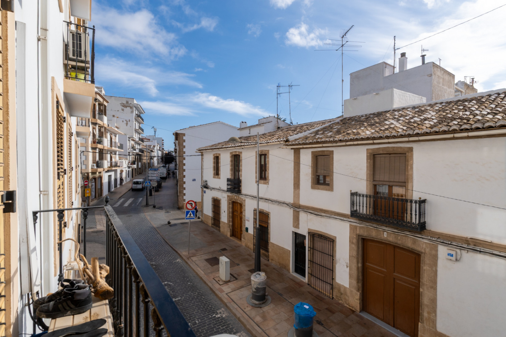 Vue depuis le balcon sur une rue du centre historique de Jávea, mettant en avant des façades blanches traditionnelles, des toits en tuiles et des encadrements en pierre.