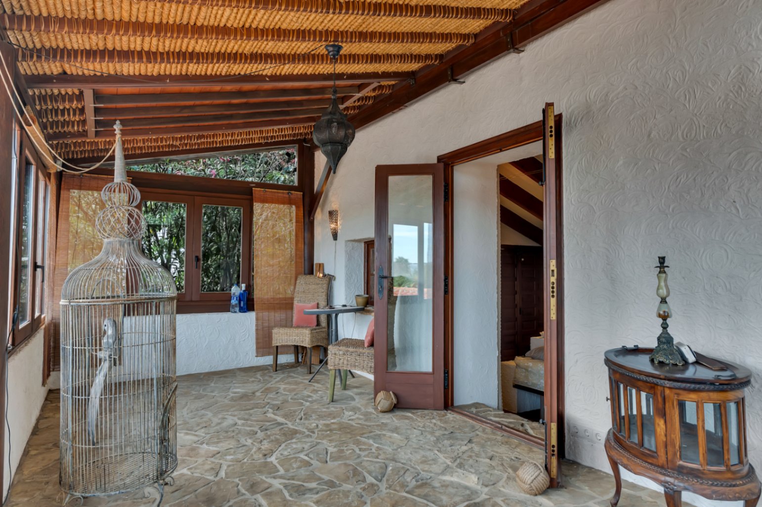 Naya traditionnelle avec sol en pierre naturelle, plafond en poutres de bois et roseaux. Elle dispose de meubles en osier et d'un accès direct à l'intérieur par des portes vitrées.