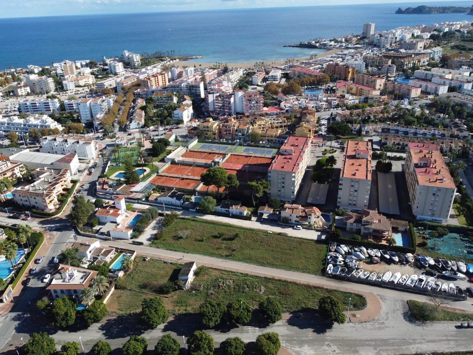 Vue aérienne du terrain à bâtir à Jávea, jouxtant le club de tennis et offrant une proximité directe avec la plage de l'Arenal et le littoral méditerranéen.