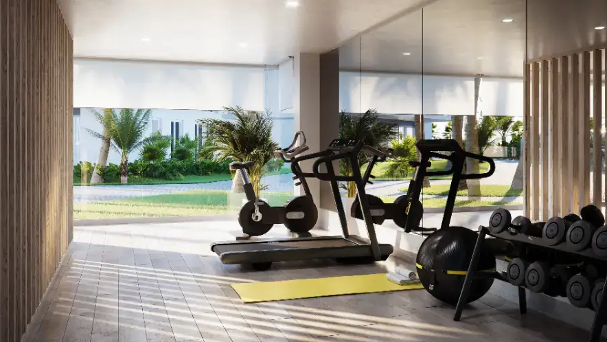 Salle de sport moderne équipée d'appareils de cardio, de poids libres et de grandes baies vitrées offrant une vue sur les jardins. Murs en lattes de bois et éclairage encastré.