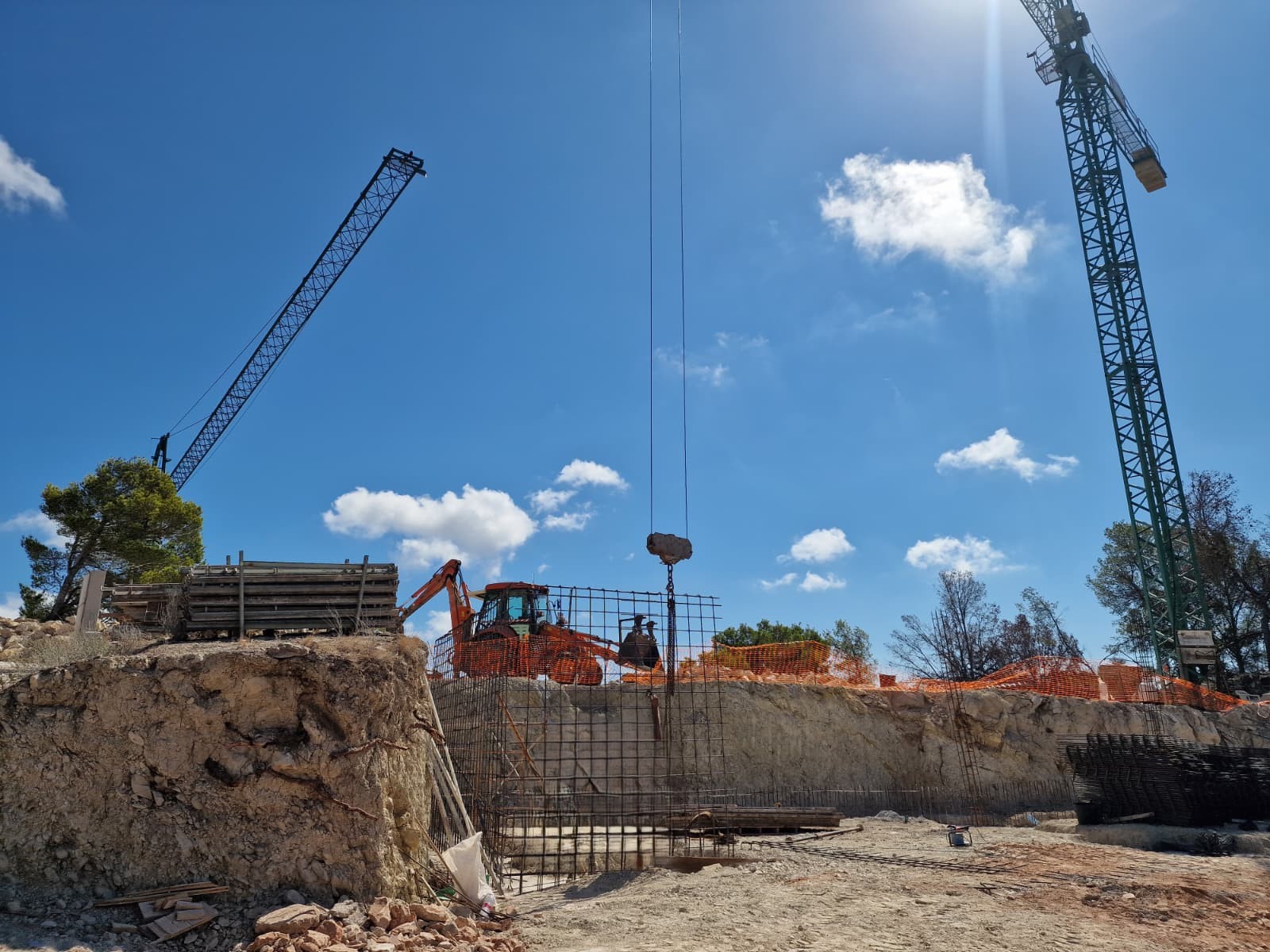 Avancement des travaux à Moraira présentant le terrassement, le ferraillage des fondations et l'installation des grues de construction sur le site.