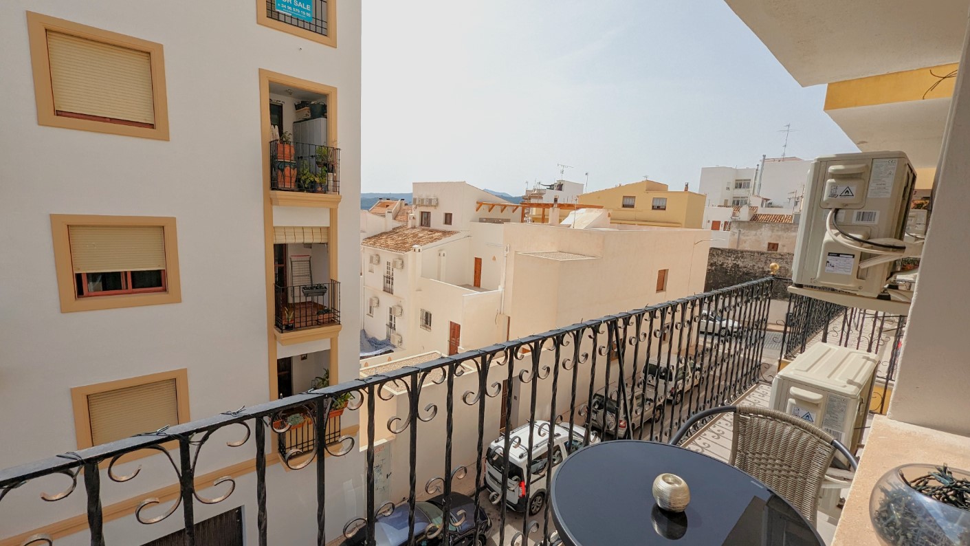 Balcon privé avec garde-corps en fer forgé, comprenant un petit salon de jardin et offrant une vue sur les bâtiments typiques de la vieille ville de Javea.