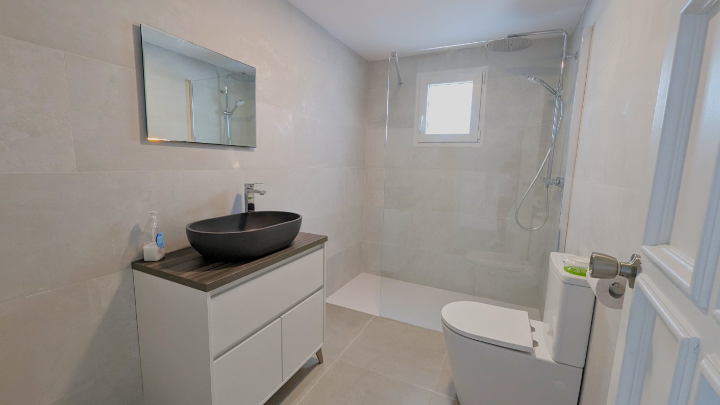 Salle de bain moderne équipée d'une vasque noire, d'une douche à l'italienne avec paroi en verre et de carrelage gris contemporain.