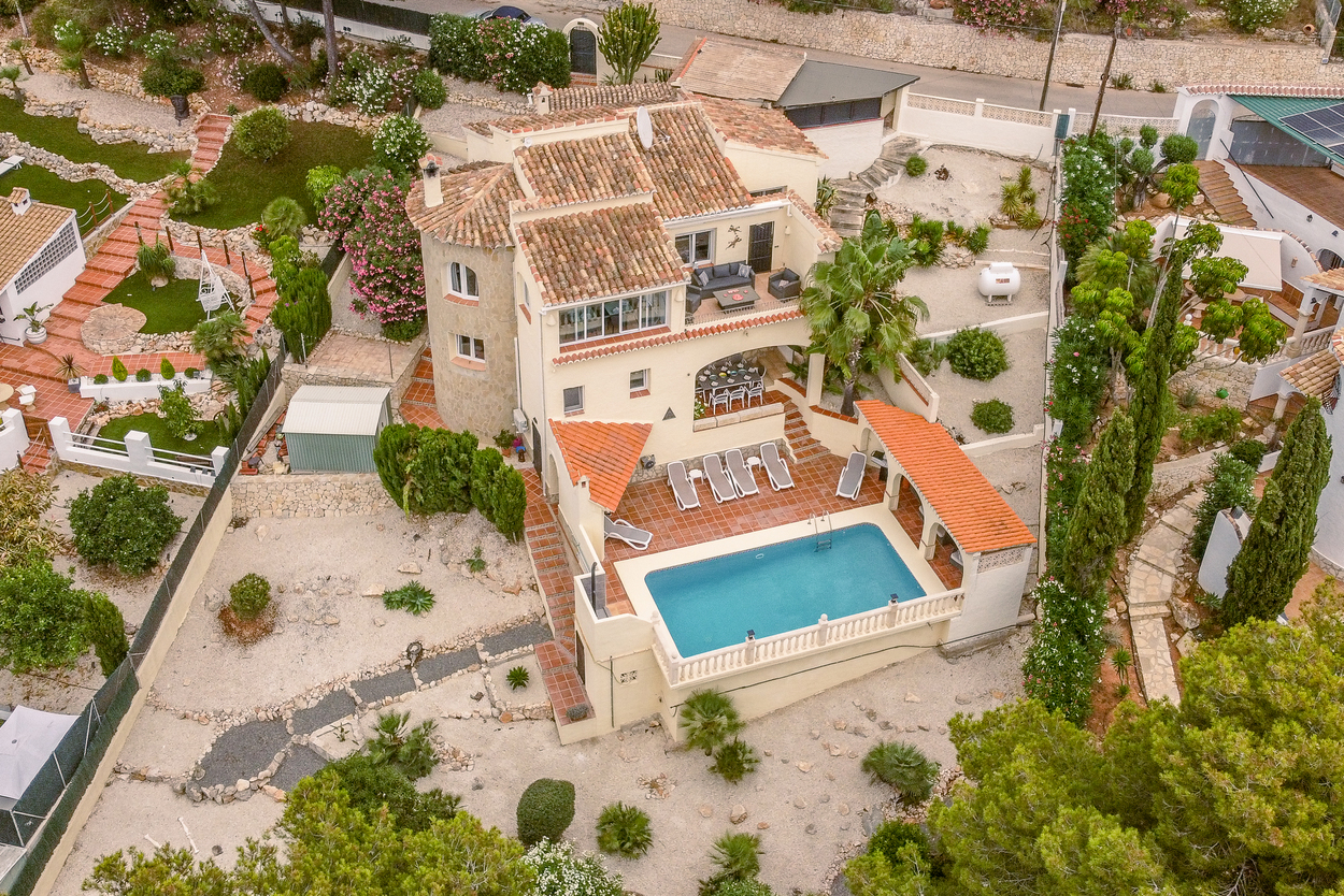 Vue aérienne de la villa avec piscine 8x4m, terrasses en terre cuite et tour en pierre, le tout niché dans un jardin méditerranéen paysager.