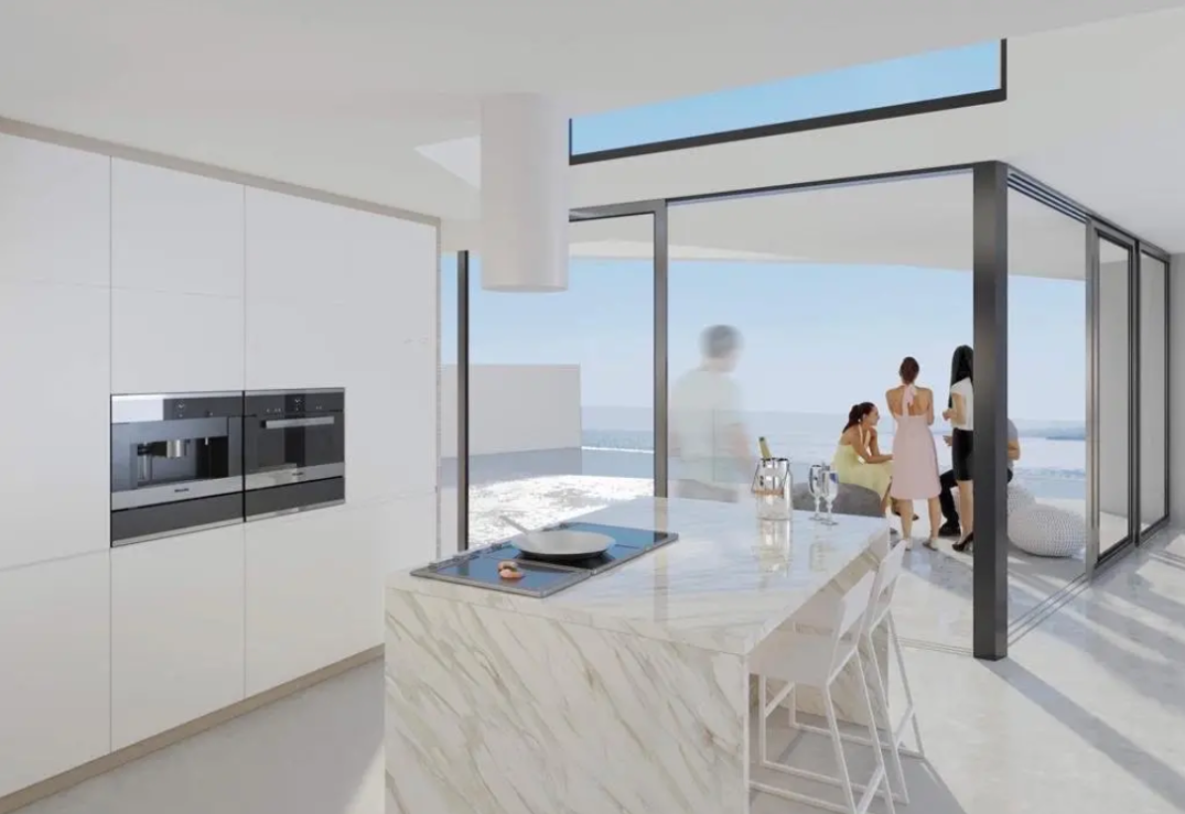 Cuisine moderne avec îlot en marbre, électroménager encastré et grandes baies vitrées offrant un accès direct à la terrasse avec vue sur la mer.