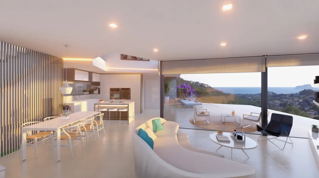 Espace de vie ouvert avec canapé incurvé, salle à manger et cuisine avec îlot. De larges baies vitrées s'ouvrent sur une terrasse offrant une vue panoramique sur la mer Méditerranée.