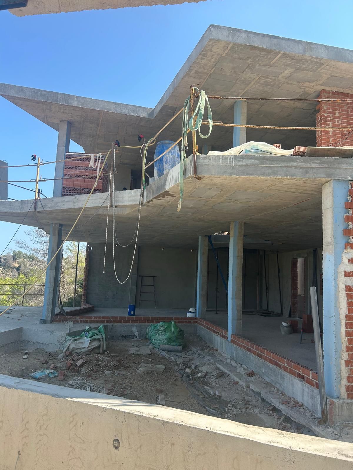 Phase structurelle d'une villa à plusieurs niveaux à Benitachell, avec dalles en béton armé, piliers et maçonnerie initiale en briques.