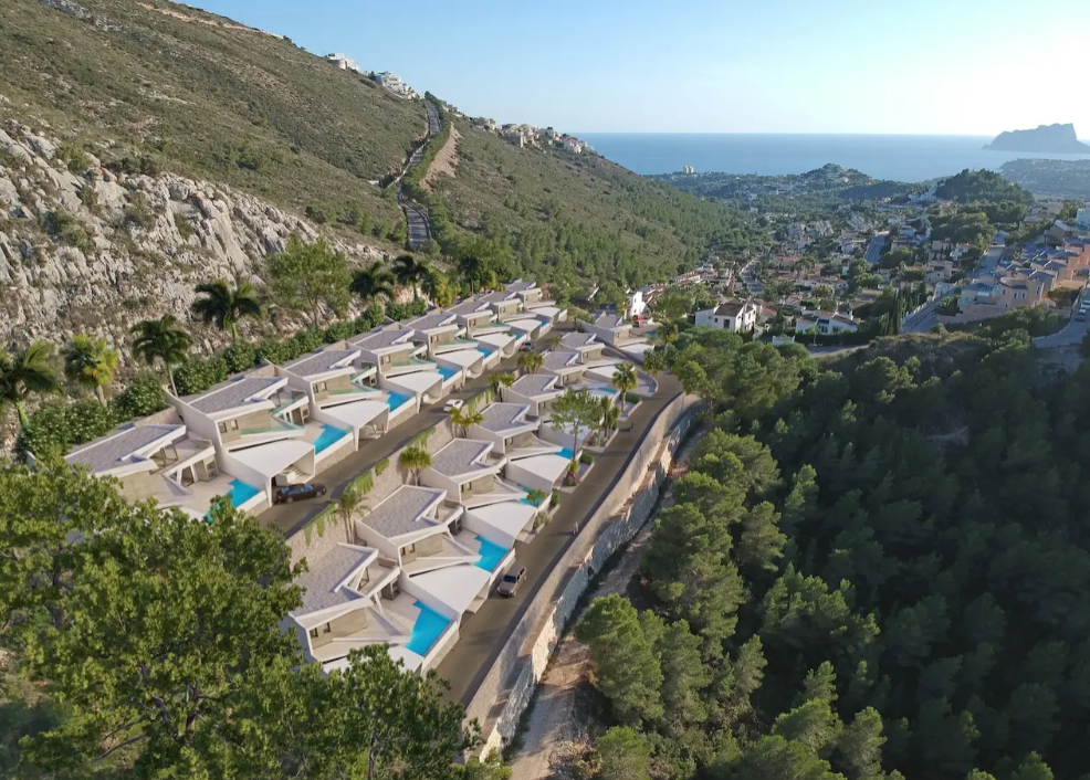 Vue aérienne de seize villas modernes en terrasses à Benitachell, dotées de piscines privées et offrant un panorama sur la côte méditerranéenne et le Peñón de Ifach.