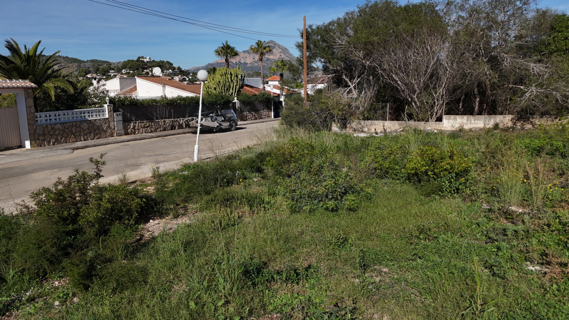 Terrain plat à Pinosol, Jávea, offrant un accès direct par rue goudronnée et une vue dégagée sur le Montgó dans un quartier résidentiel calme.