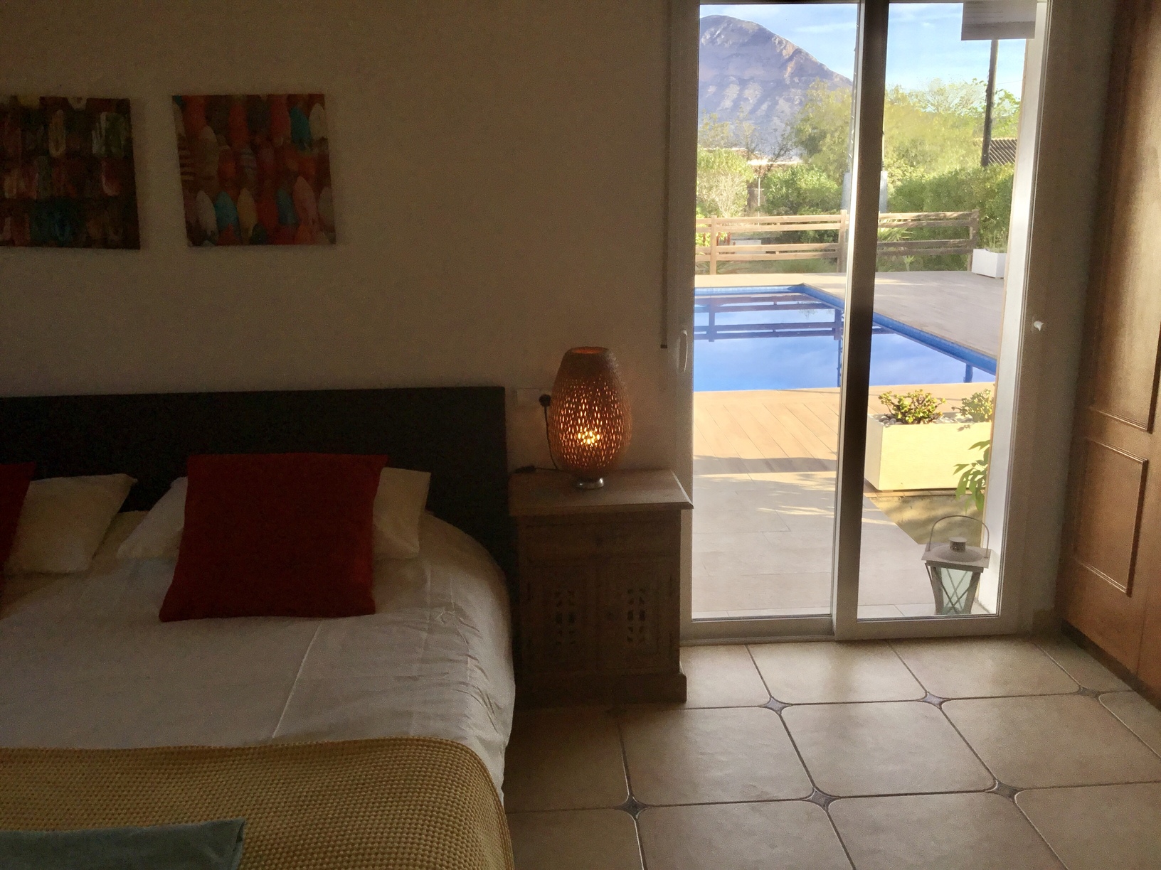 Chambre avec accès direct à la terrasse de la piscine par des baies vitrées, offrant une vue sur le Montgó et un sol en carrelage.