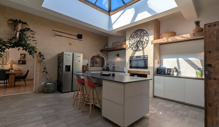 Cuisine moderne dotée d'un grand dôme vitré, d'un îlot central avec assises et de murs en pierre ornés d'outils traditionnels et décoratifs.