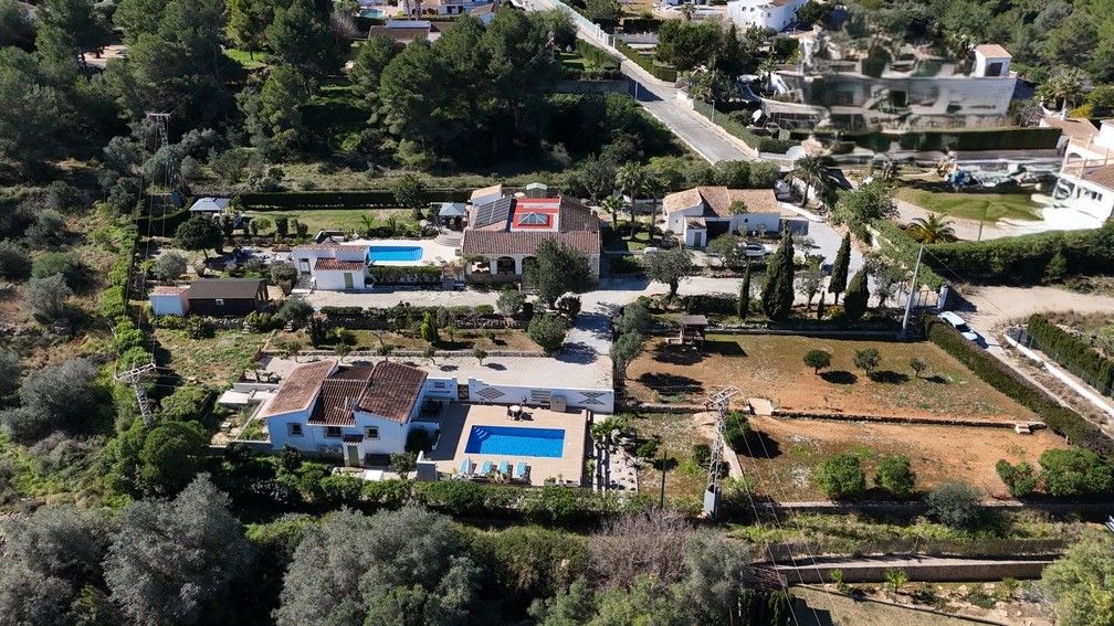Vue aérienne du terrain de 4 600 m² présentant deux villas indépendantes avec piscines privées, un chalet en bois et la maison principale équipée de panneaux solaires.