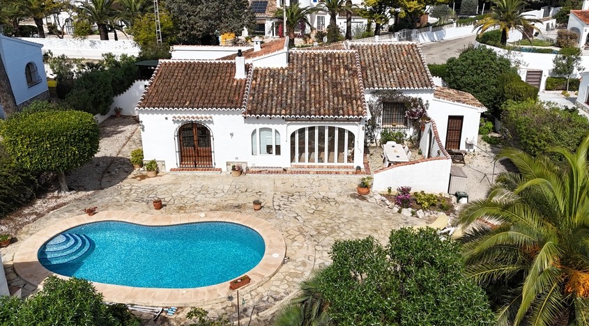Vue aérienne de la villa avec piscine en forme de haricot, vaste terrasse en pierre et architecture méditerranéenne aux toits de tuiles et murs blancs.