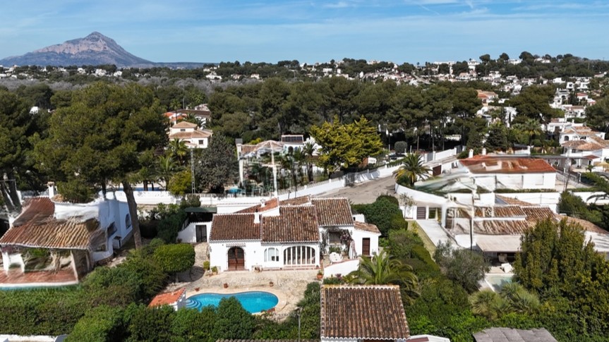 Vue aérienne de la villa traditionnelle avec piscine privée, toits en terre cuite et jardin arboré, offrant une vue sur le mont Montgó.