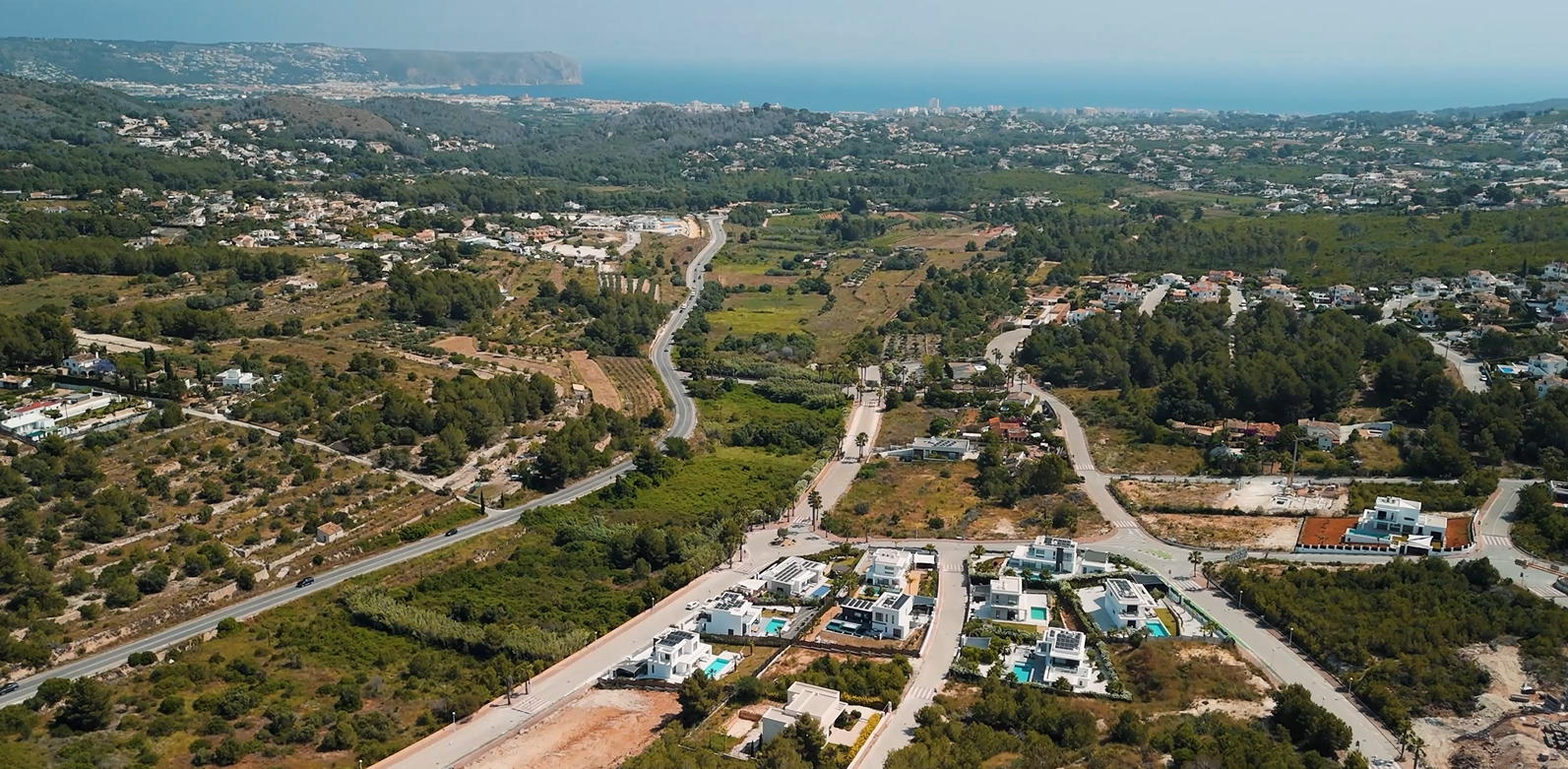Vue aérienne du quartier résidentiel Villas del Vent à Jávea, présentant des villas modernes et des terrains avec vue panoramique sur la mer Méditerranée.