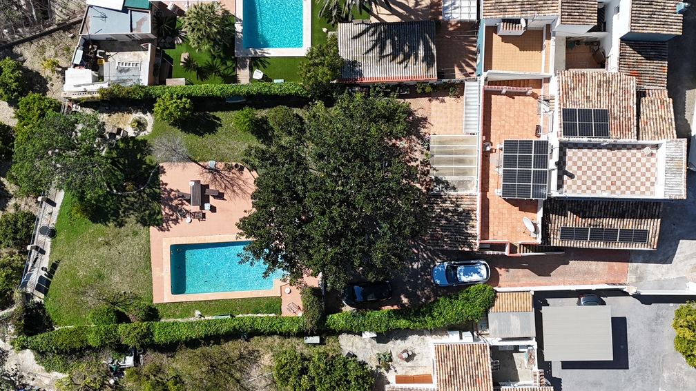Vue aérienne de la villa comprenant une piscine privée, un jardin et des panneaux solaires sur le toit en terre cuite, entourée de verdure méditerranéenne.