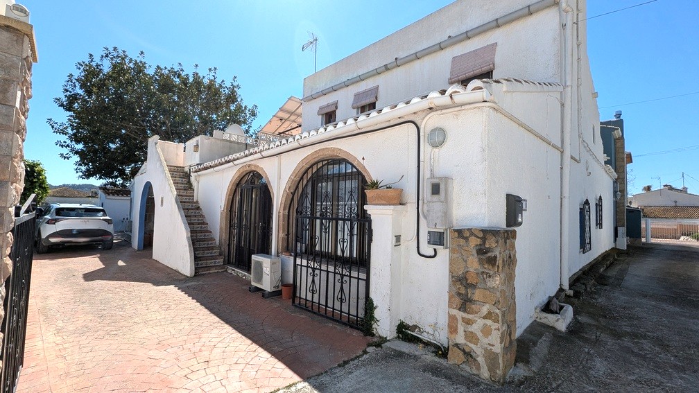 Vue extérieure présentant des arches en pierre Tosca, des grilles en fer forgé, un escalier extérieur carrelé et des panneaux solaires installés sur le toit.