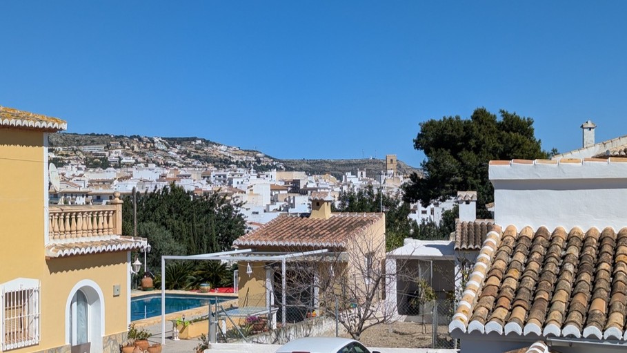 Vue panoramique depuis la terrasse supérieure sur le village de Javea, illustrant les toits en terre cuite, la piscine privée et les collines environnantes.