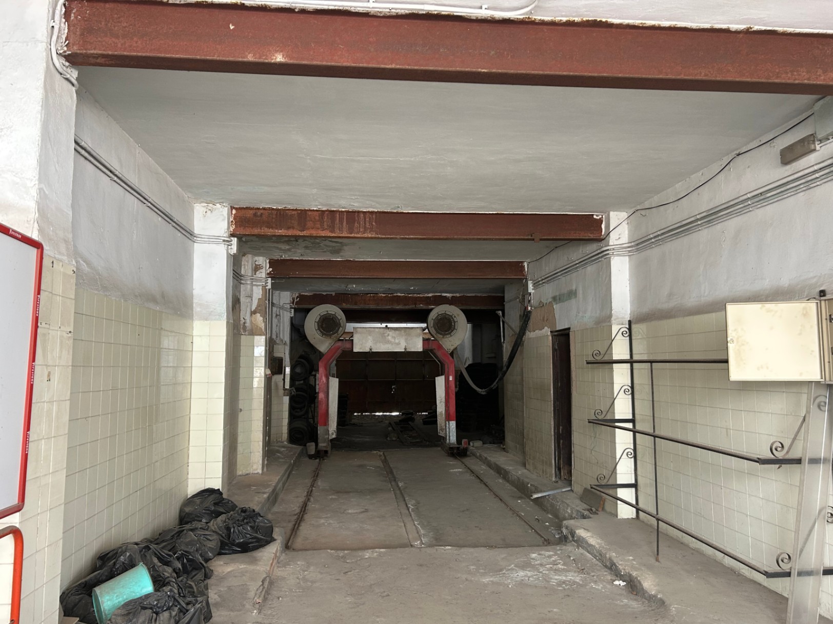 Local commercial de 175 m² au rez-de-chaussée avec de hauts plafonds, des poutres en acier apparentes et des rails industriels, idéal pour un projet de rénovation.